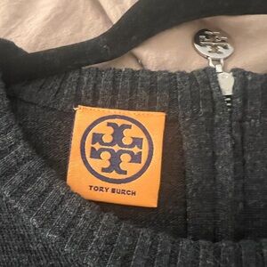 Gray wool sweater with metallic emblem. Size large . Zipper at neck.